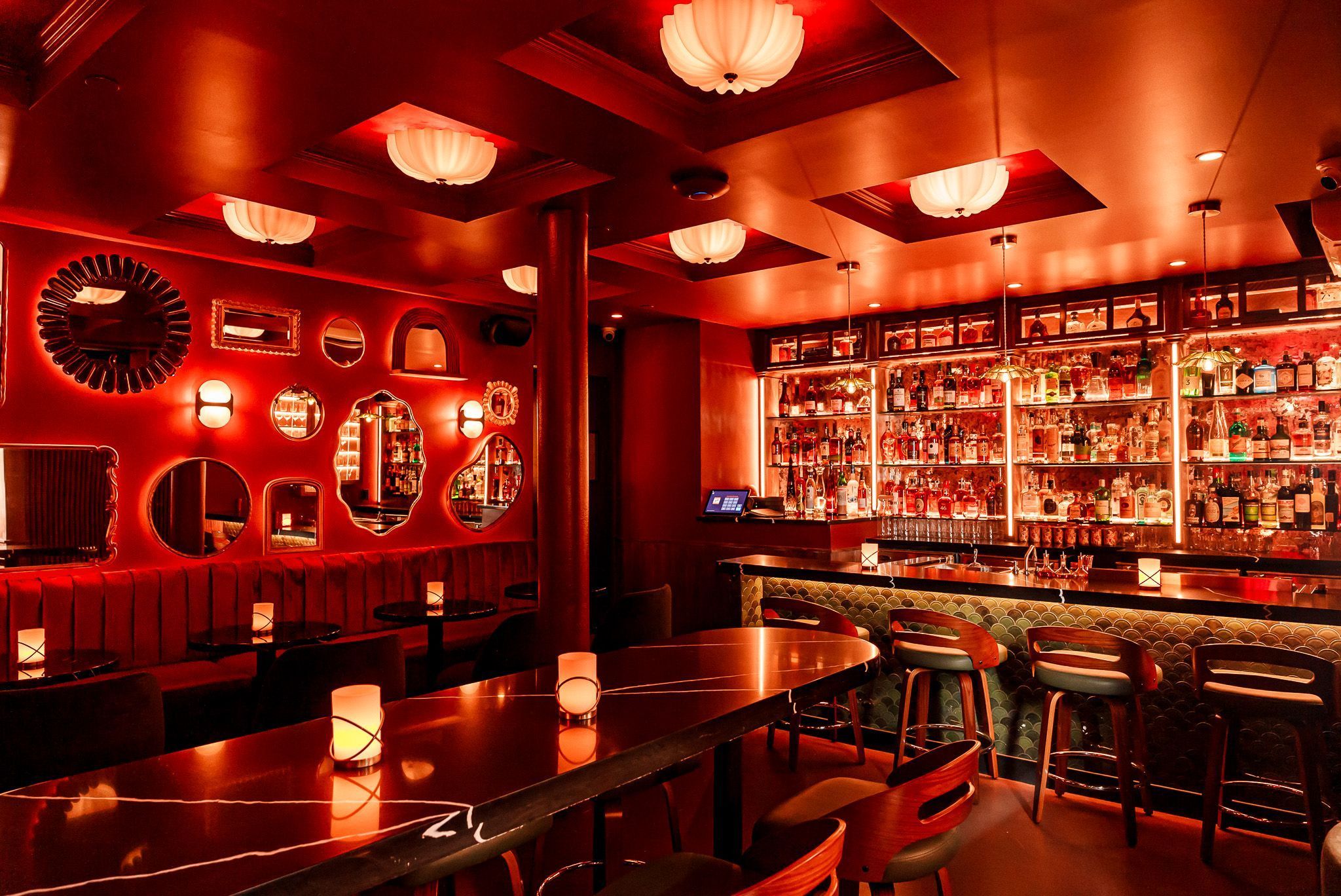 Cozy bar interior of Room 207 with warm red lighting, vintage mirrors on walls, and a well-stocked cocktail bar.