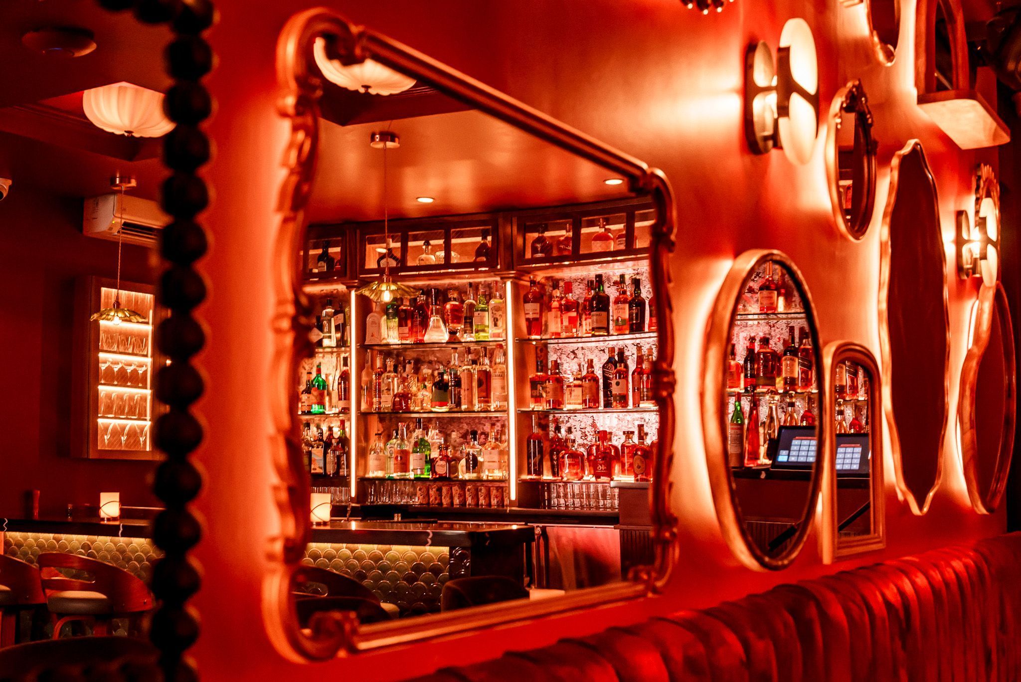 Cozy bar interior at Room 207 with warm lighting, vintage mirrors, and a well-stocked cocktail shelf.