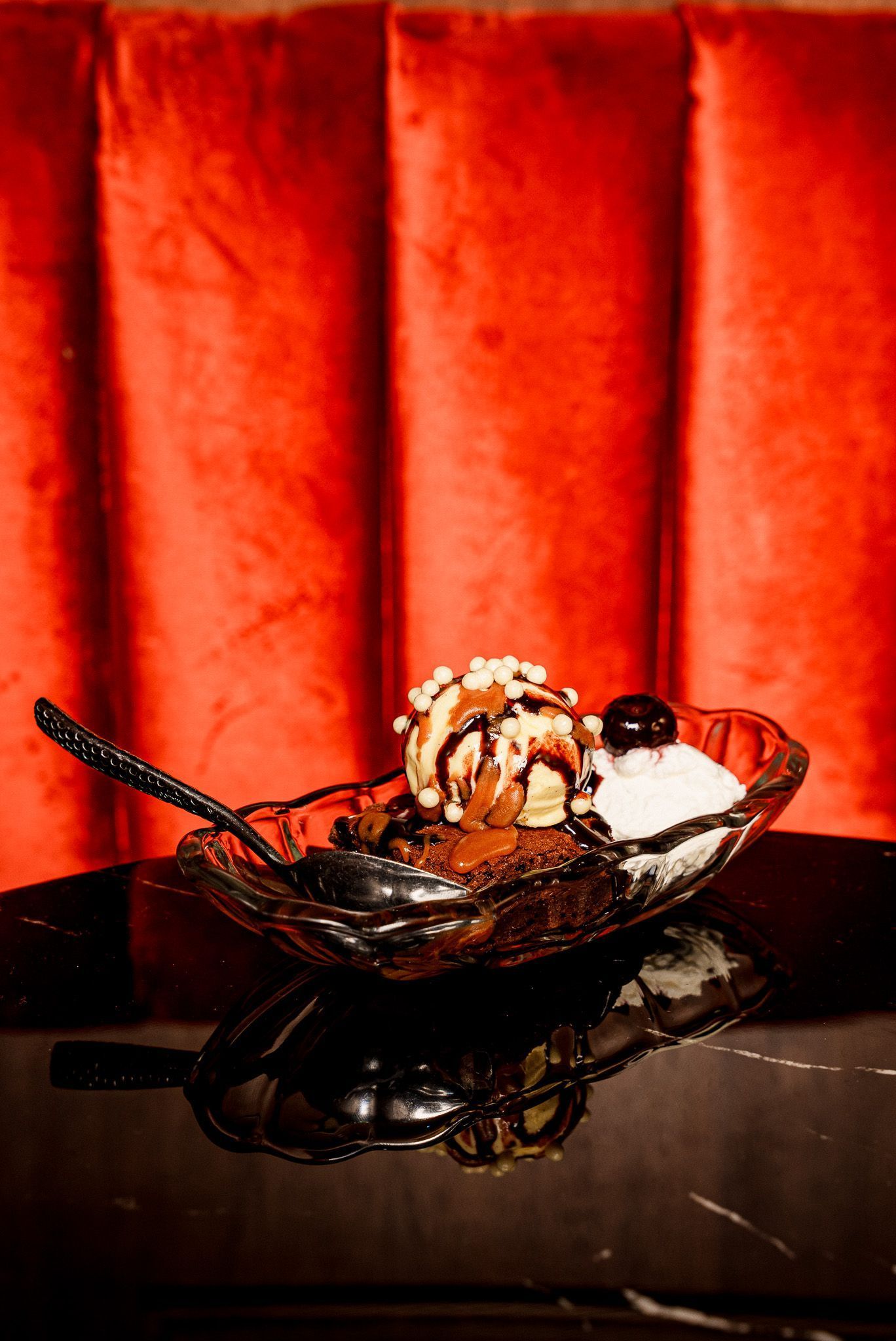 Dessert served in a glass dish on a black table with a red upholstered background in Room 207